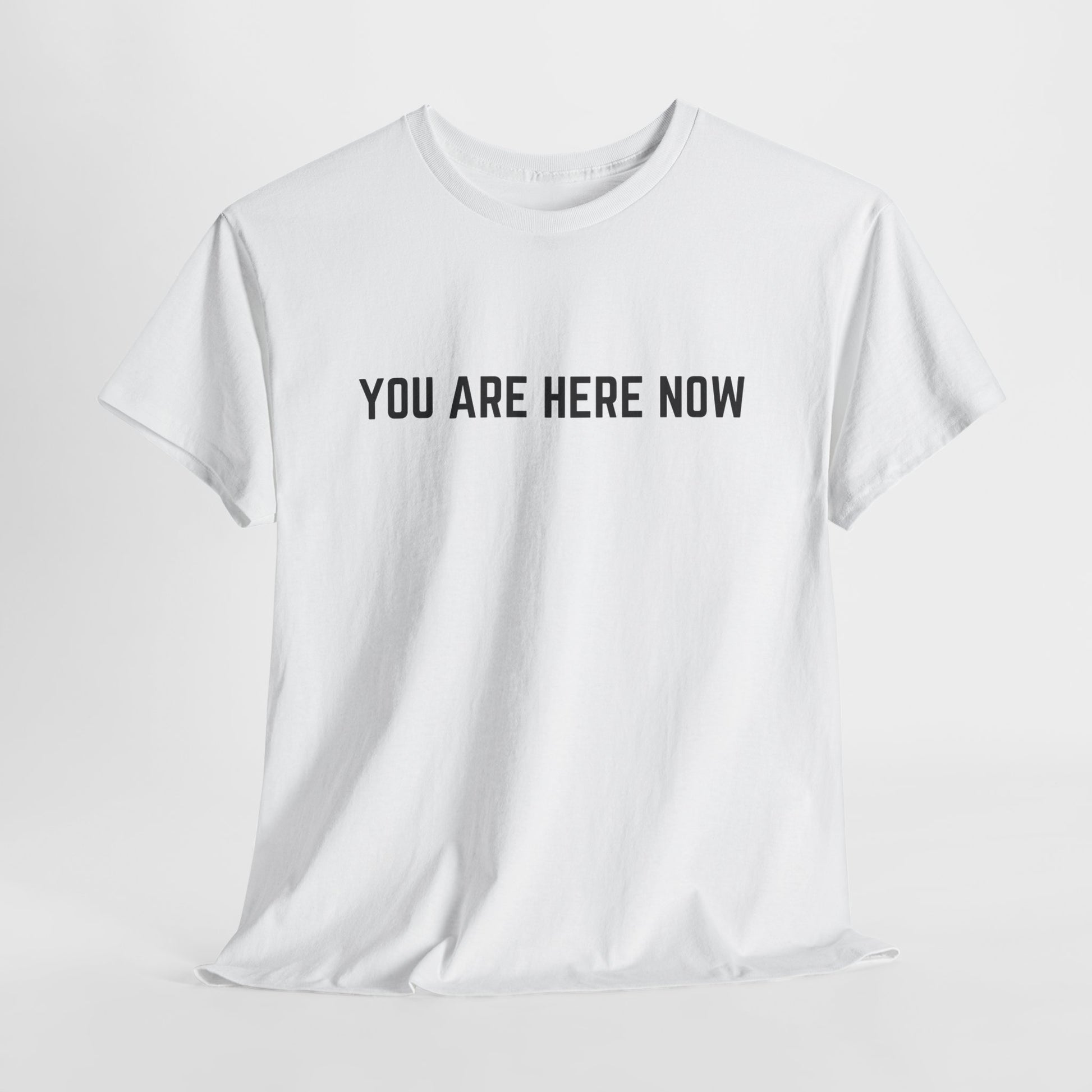 Front of a t-shirt with the grounding phrase "You are Here now" in a clean, minimalist font.
