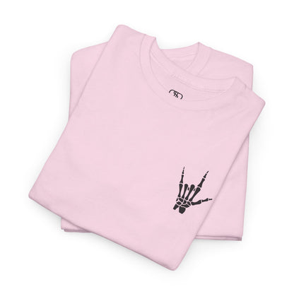A folded light pink t-shirt with small rock hand symbol on front, and "Rules.. Never Heard of Them" graffiti text on the back.
