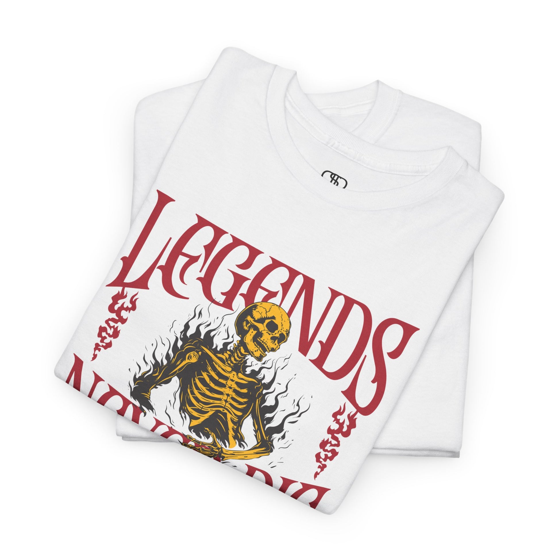 A folded white t-shirt with a graphic of a defiant skeleton engulfed in flames. The words “Legends Never Die” are prominently displayed, with a smaller quote and the word “Immortal” included in the design.