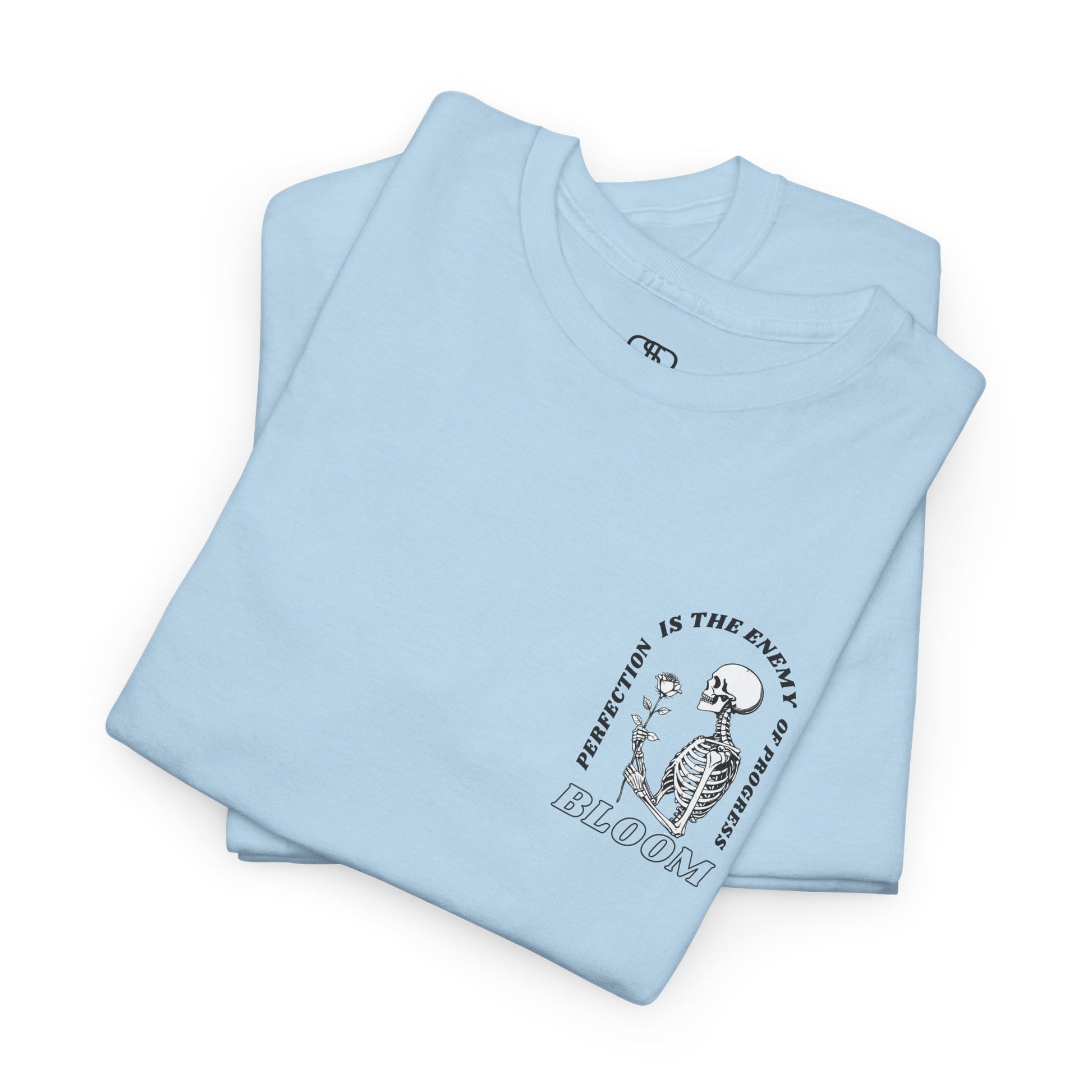 A [folded light blue] t-shirt with a central skeleton and rose design and the words “Perfection is the enemy of progress” and “Bloom” on the front.