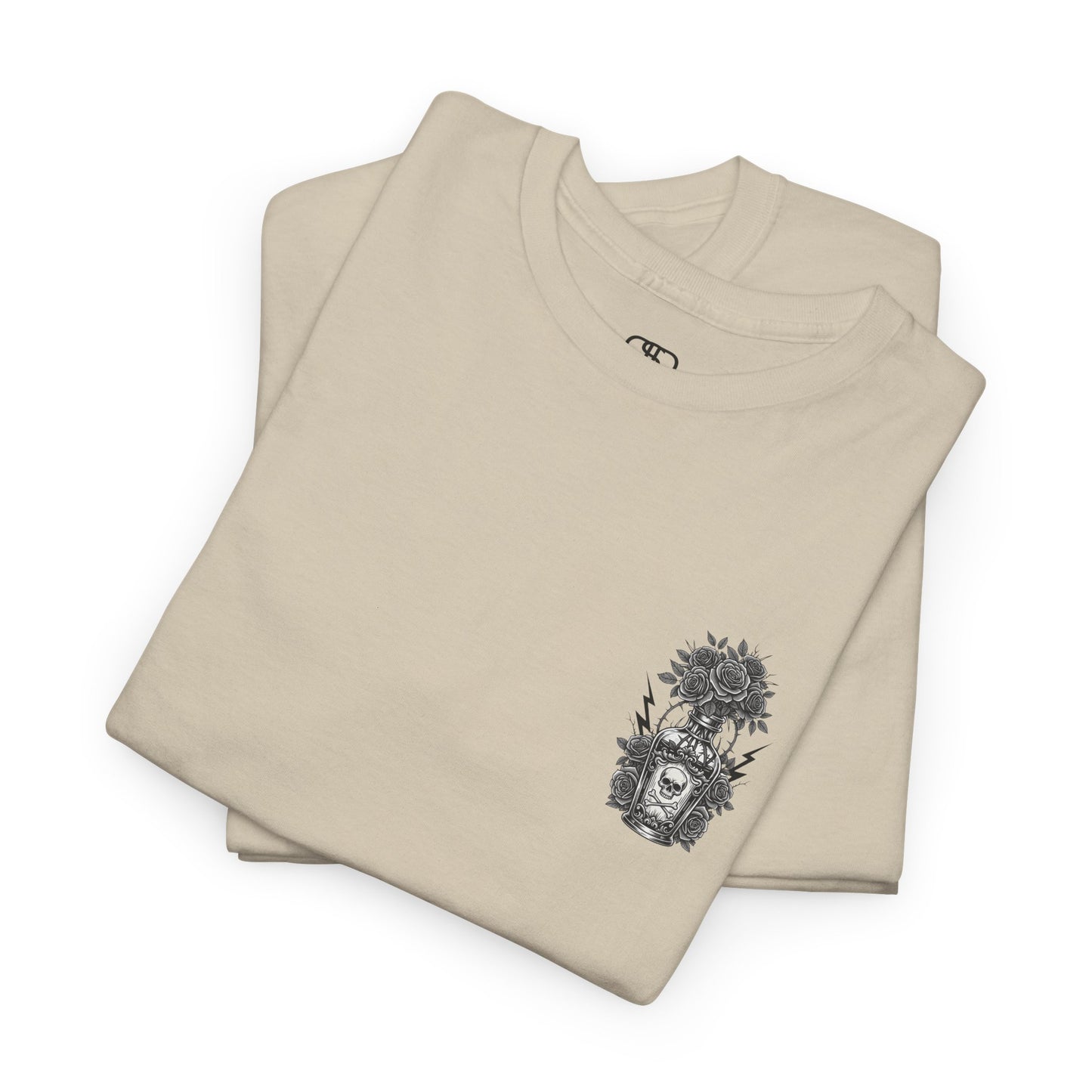 A folded sand t-shirt with a skull and crossbones vase filled with roses and the words “Surviving Purely Out of Spite” in a gothic font.