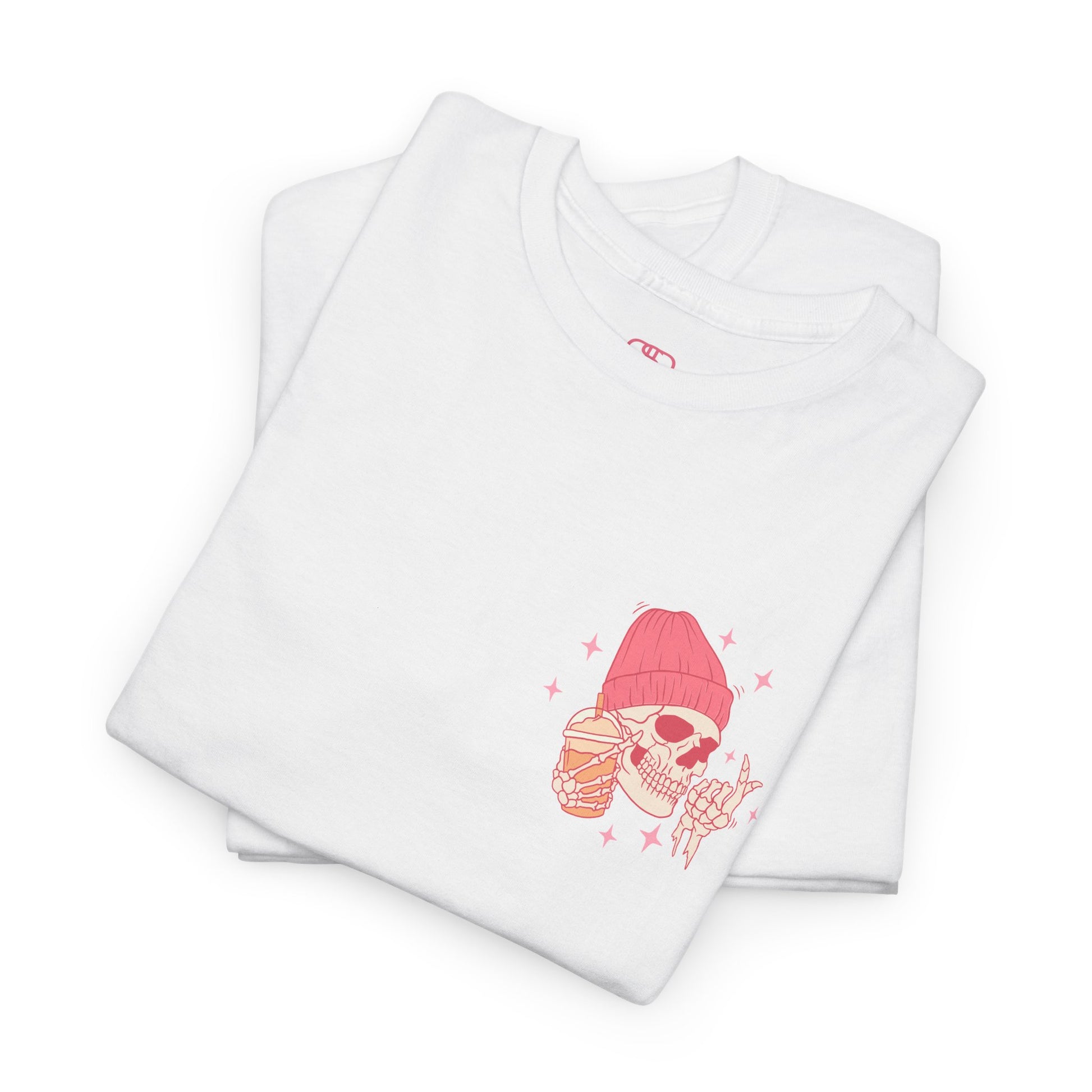 A WHITE FOLDED T-shirt with a skeleton in a pink beanie holding a frozen coffee, snapping fingers, surrounded by sparkles graphic.