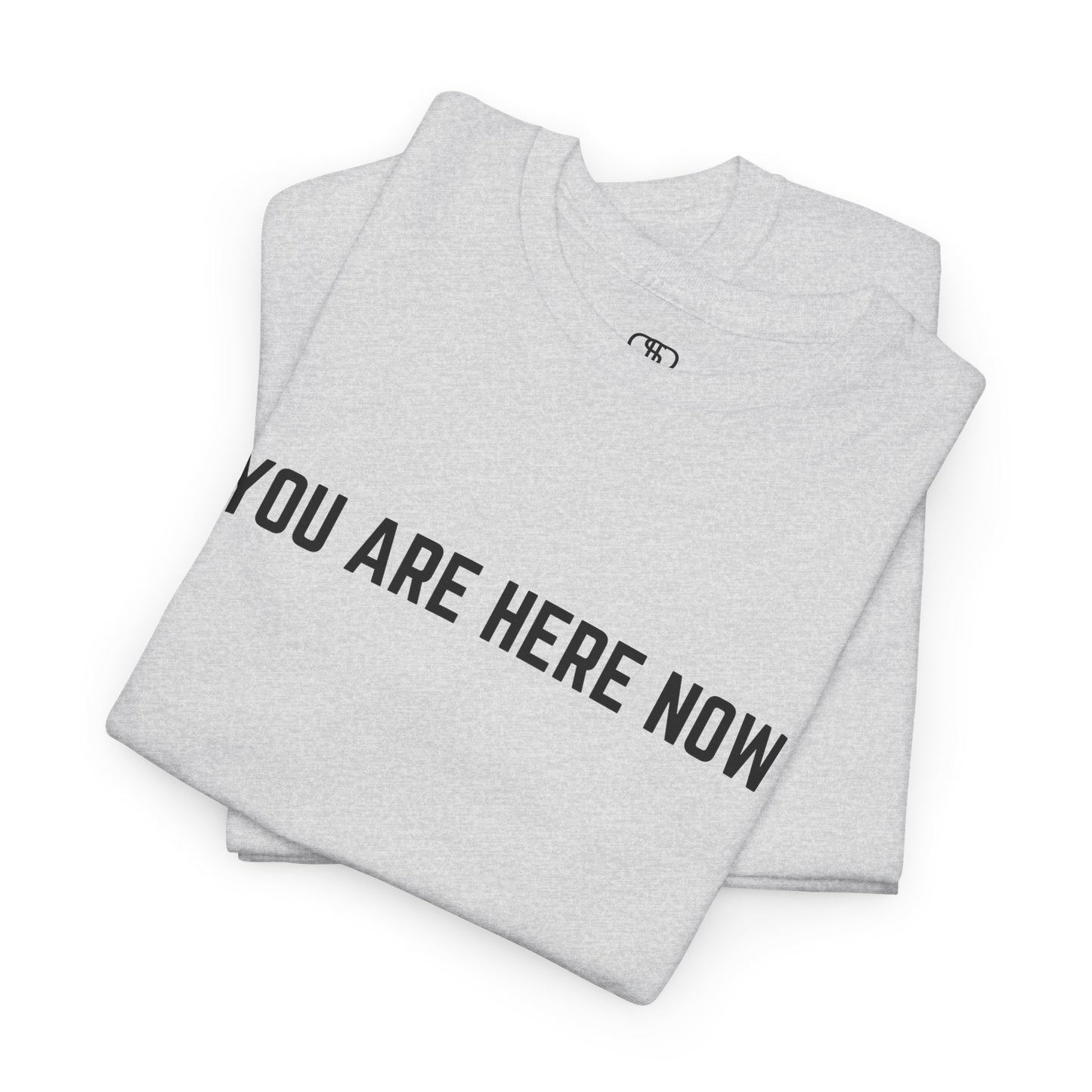 A folded ash t-shirt with the words You Are Here Now