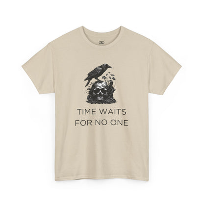 A close-up of a t-shirt with a gothic illustration. A black crow stands atop a weathered skull, which has moss and delicate vines growing through its eye sockets and around its form, blending nature and death.