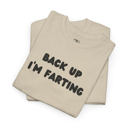 A folded sand T-shirt with the bold text "Back Up I'm Farting" on the front.