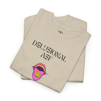 A folded sand T-shirt with "Delusional asf" text, an open mouth graphic with tongue out, and a happy face emoji pill.