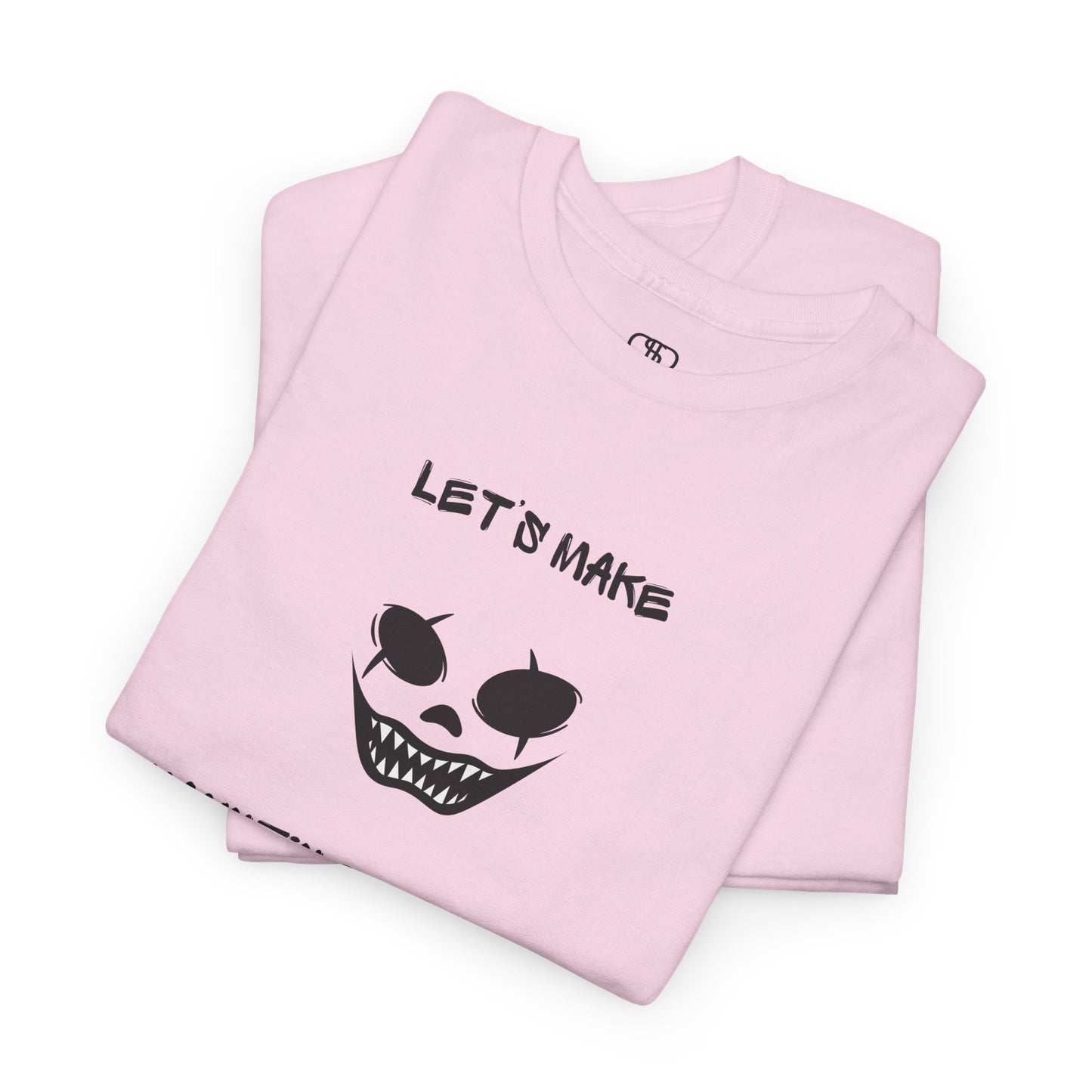 A folded light pink T-shirt with a daring clown graphic with sharp teeth and scars, and "Let’s Make Haunting Memories" text.