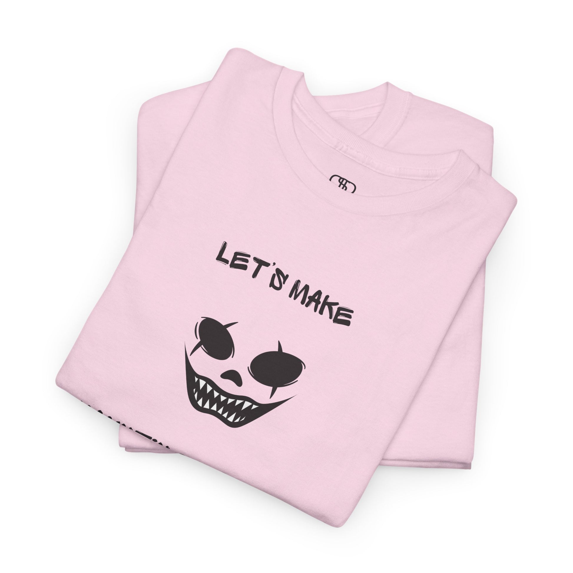 A folded light pink T-shirt with a daring clown graphic with sharp teeth and scars, and "Let’s Make Haunting Memories" text.