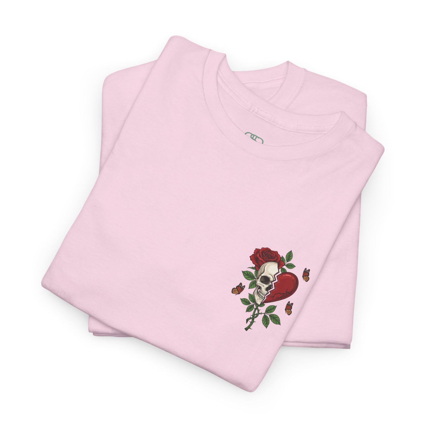 A folded light pink t-shirt with a front design of a half skull, half broken heart, and a rose. The back reads "Gym Heals" in red.