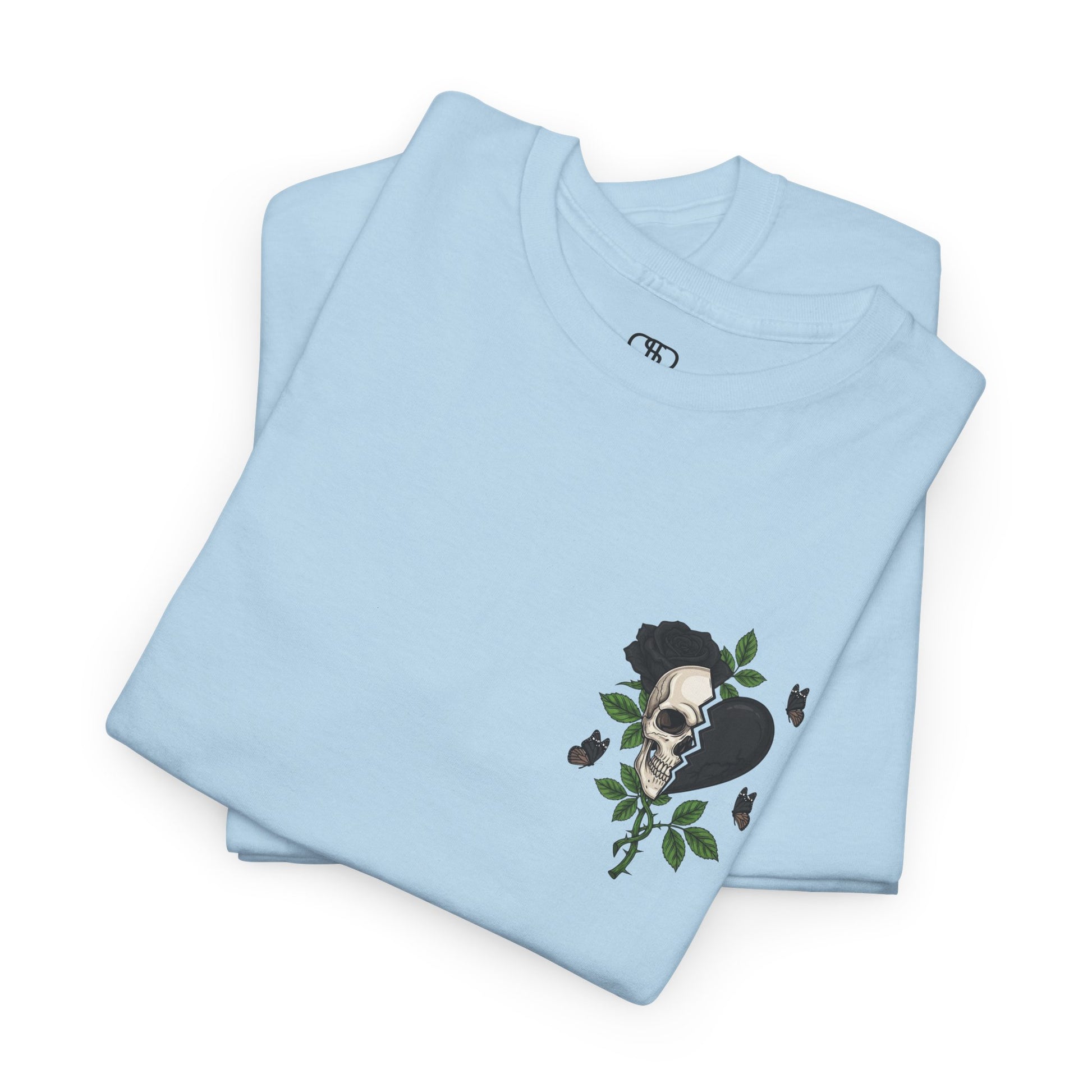 A folded light blue t-shirt with a front design of a half skull, half broken heart, and a rose. The back reads "Gym Heals" in black.