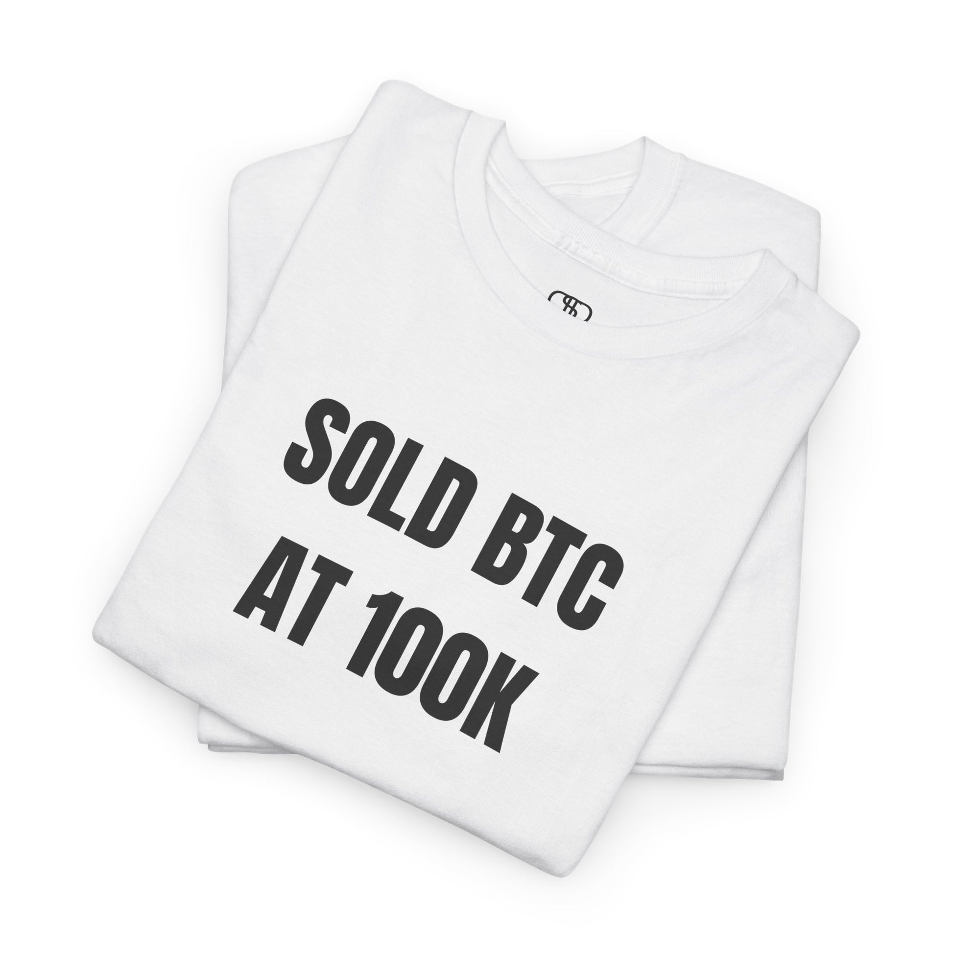 A Folded white T-shirt with bold text "SOLD BTC At 100K" on the front.