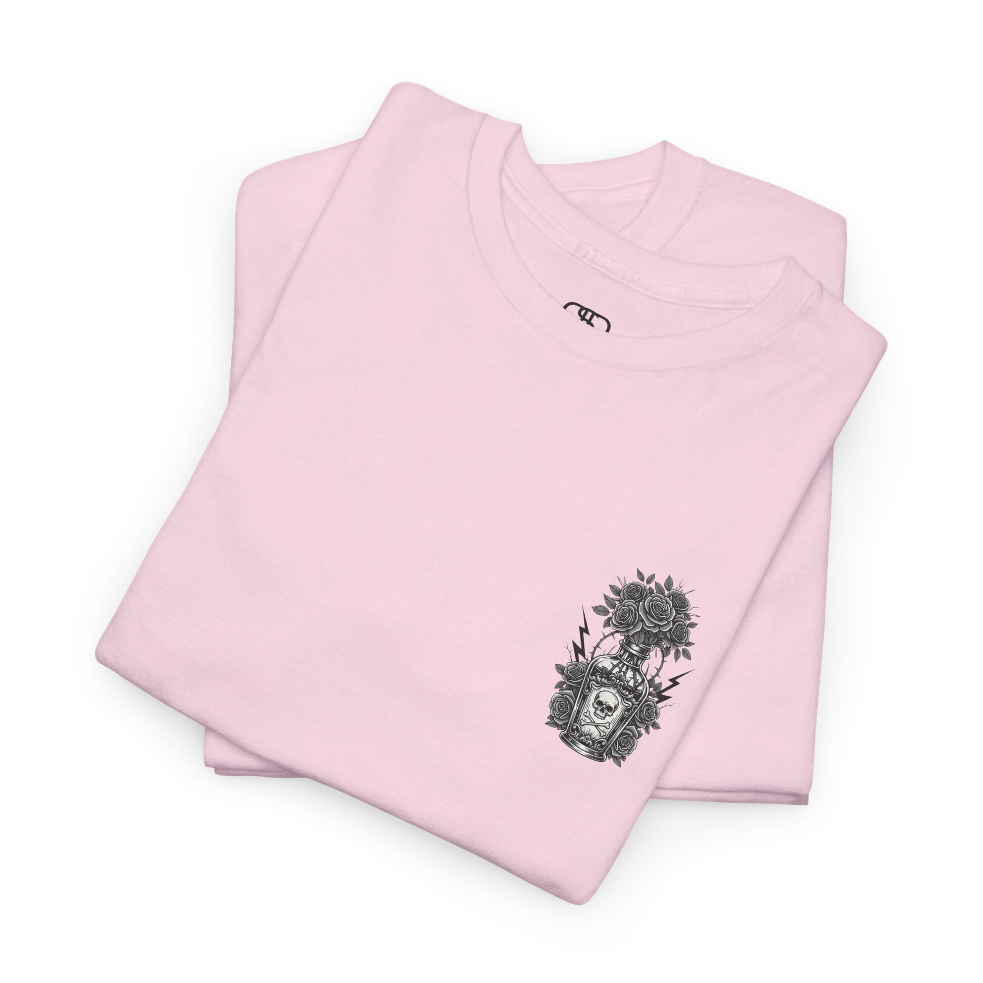 A folded light pink t-shirt with a skull and crossbones vase filled with roses and the words “Surviving Purely Out of Spite” in a gothic font.