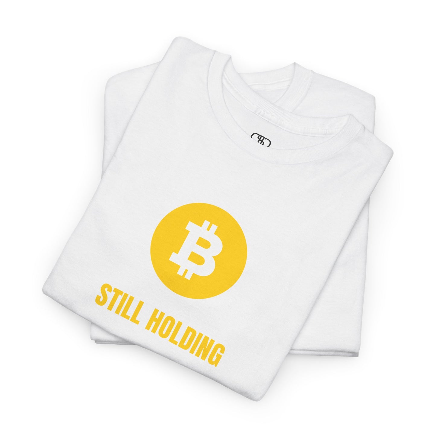 A folded white  T-shirt with a Bitcoin emblem and "Still Holding" text in gold.