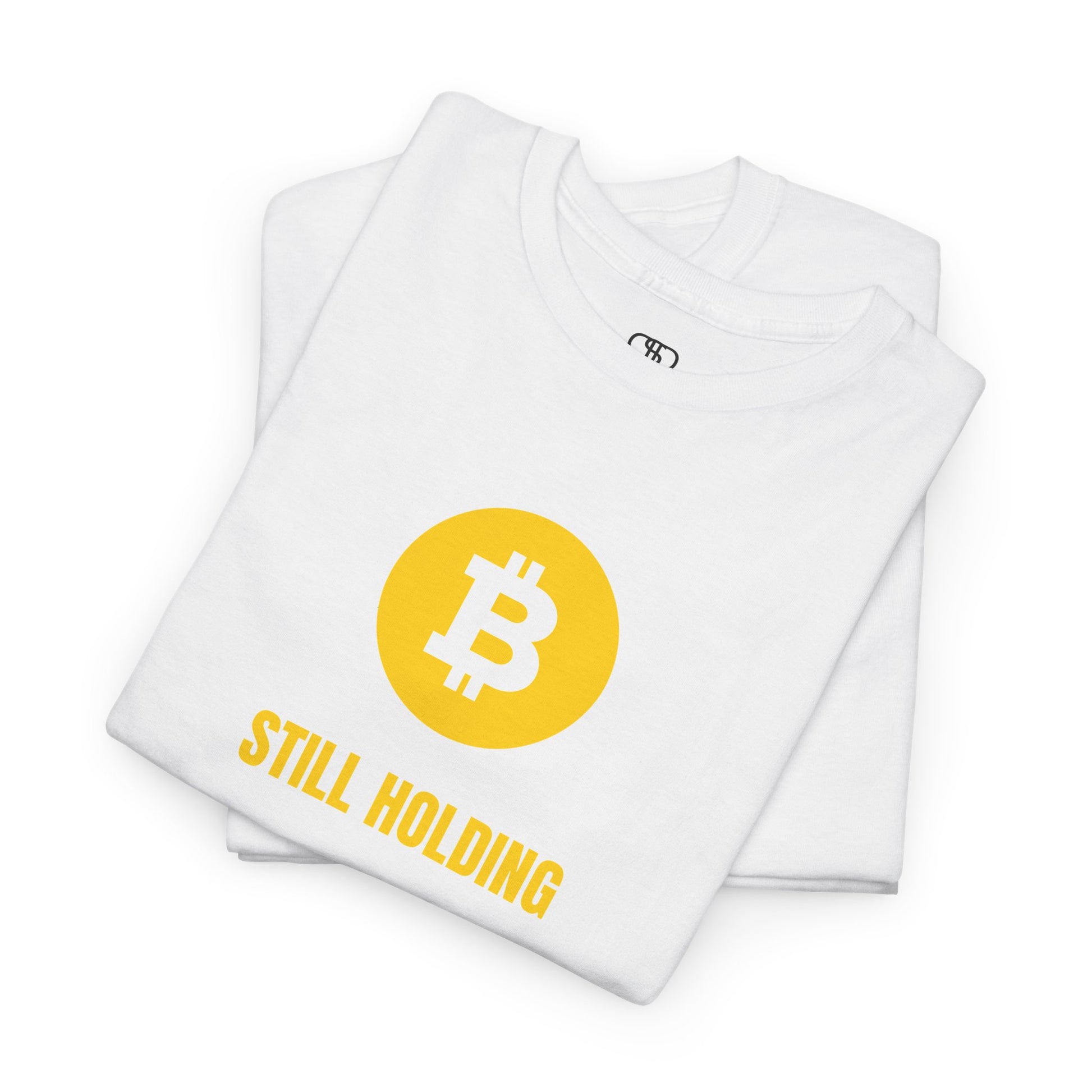 A folded white  T-shirt with a Bitcoin emblem and "Still Holding" text in gold.