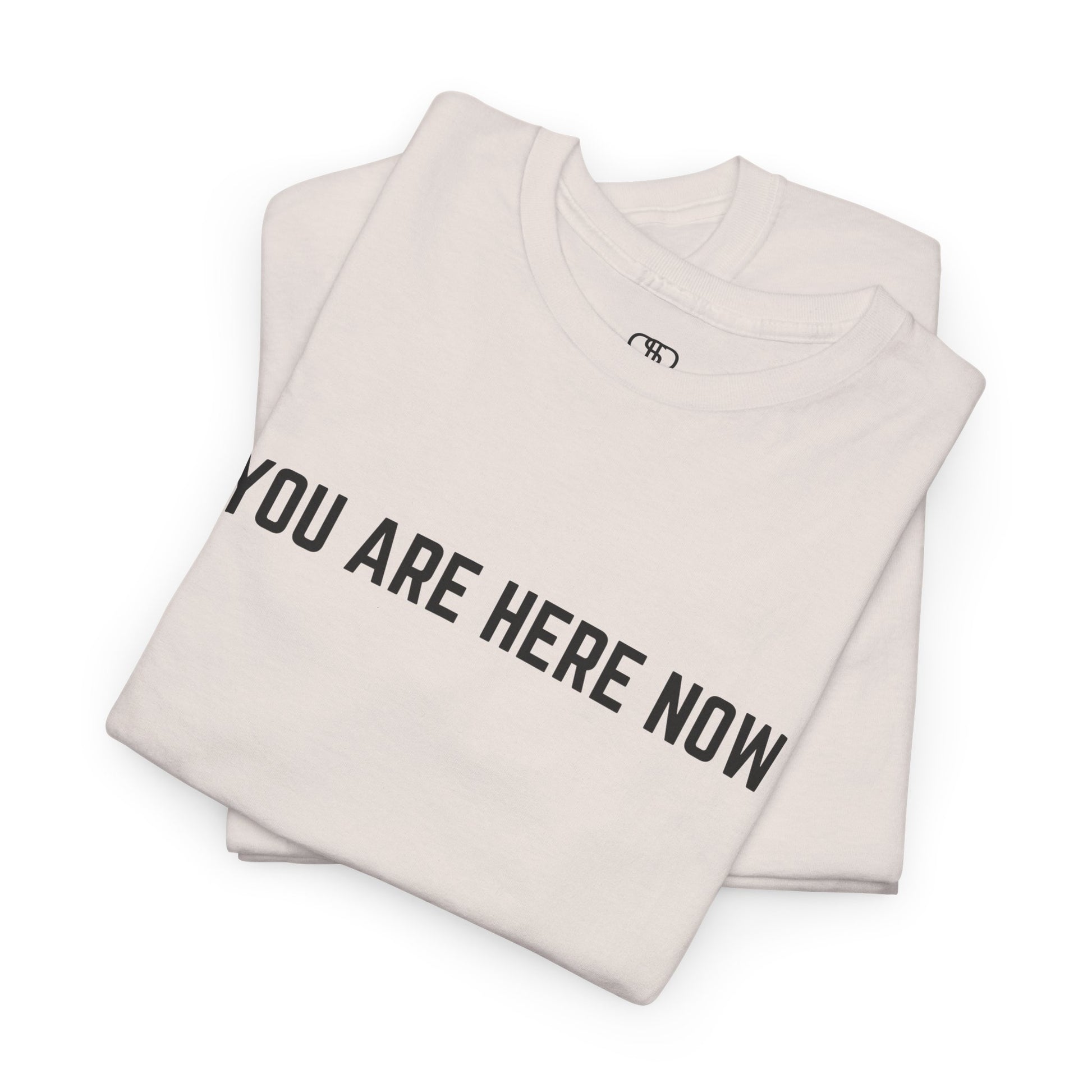A folded t-shirt with the words "You are Here Now." 
