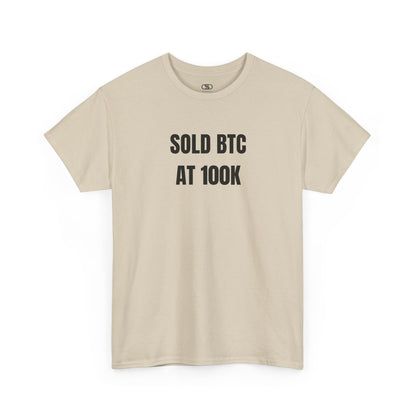 A sand T-shirt with bold text "SOLD BTC At 100K" on the front.