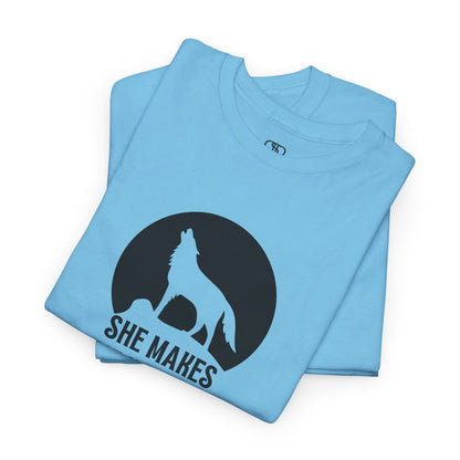 A folded sky blue  T-shirt with a wolf silhouette howling at the moon on a cliff, and "She makes me HOOWWL" text.
