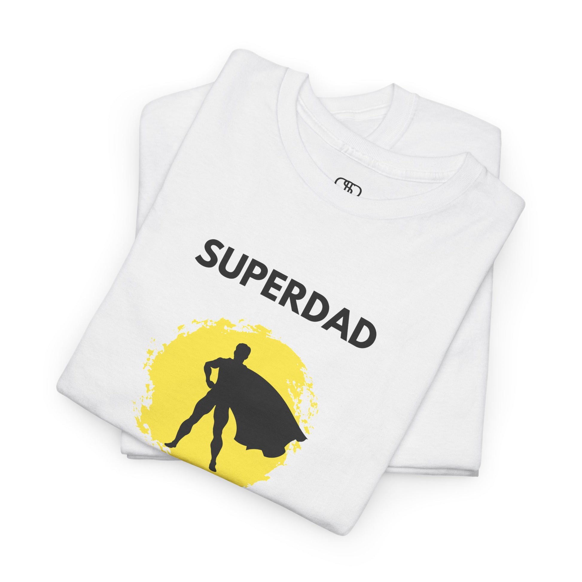A folded white T-shirt with a "Superdad" text and a silhouette of a person with a cape on a yellow circle background.