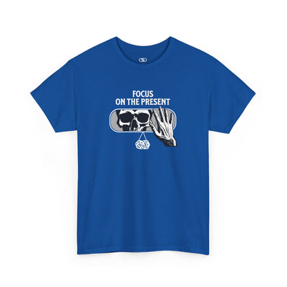 A t-shirt graphic of a car's rearview mirror reflecting a skeleton's face. A living hand reaches toward the mirror, which has dice dangling from it. The phrase “Focus on the present” is part of the design.