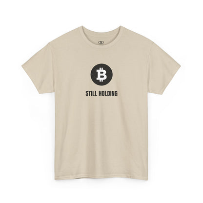 A sand T-shirt with a Bitcoin emblem and "Still Holding" text in black.