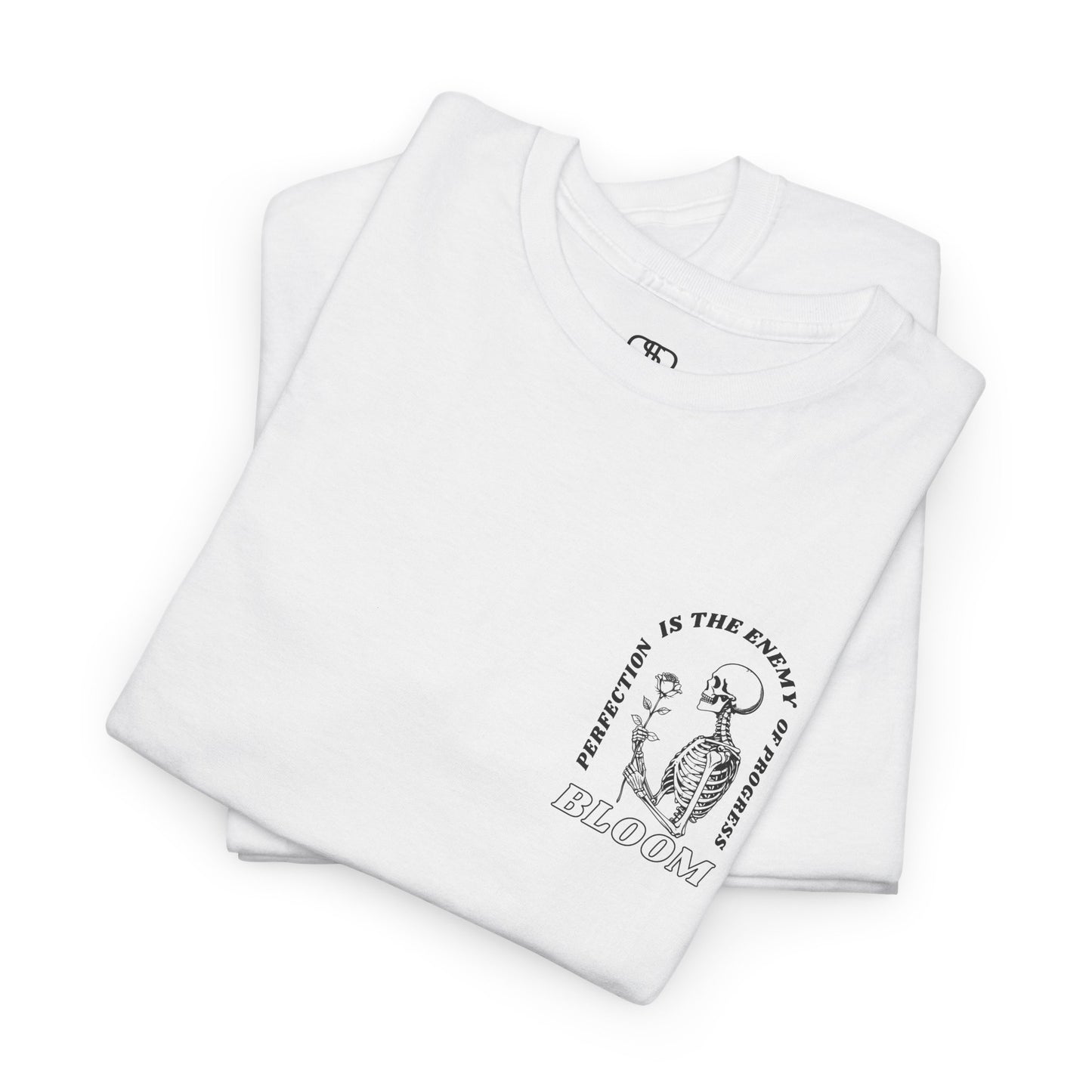 A [folded white] t-shirt with a central skeleton and rose design and the words “Perfection is the enemy of progress” and “Bloom” on the front.