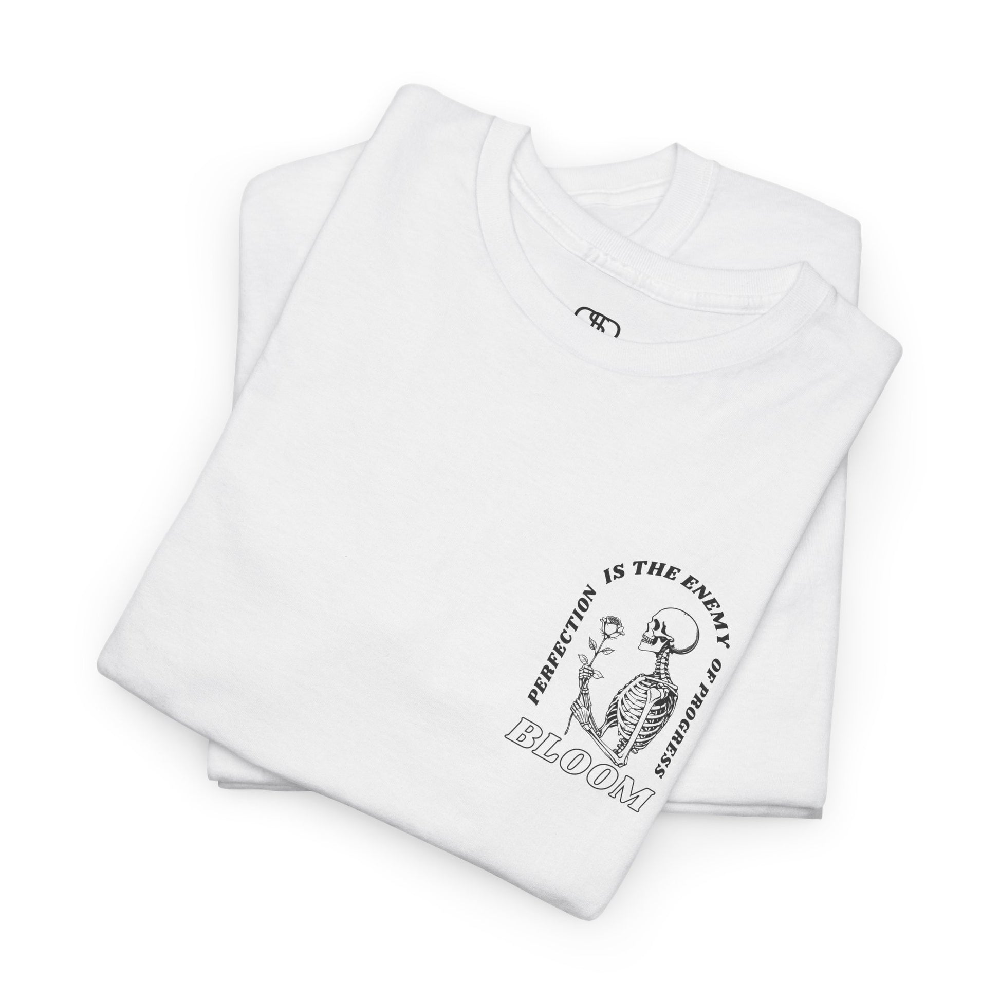 A [folded white] t-shirt with a central skeleton and rose design and the words “Perfection is the enemy of progress” and “Bloom” on the front.