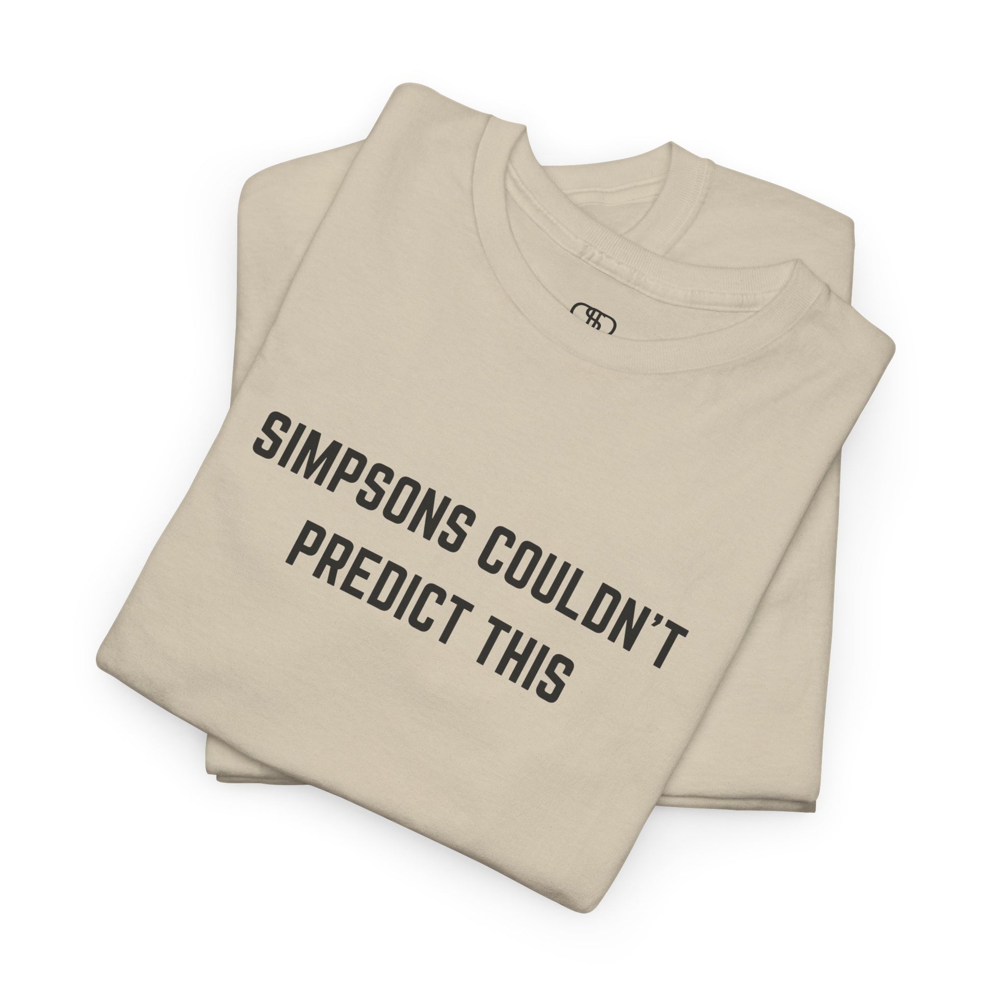 A folded sand T-shirt with the text "Simpsons Couldn't Predict This."
