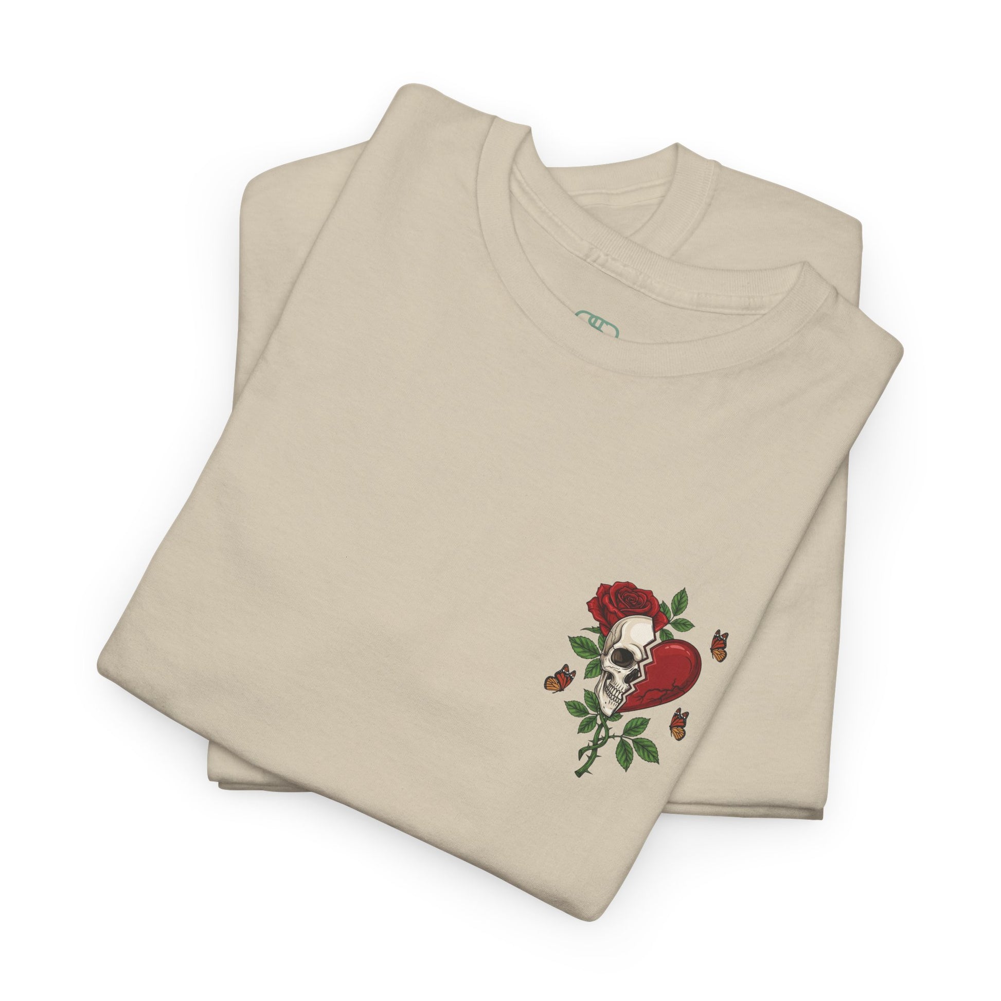 A folded sand t-shirt with a front design of a half skull, half broken heart, and a rose. The back reads "Gym Heals" in red.