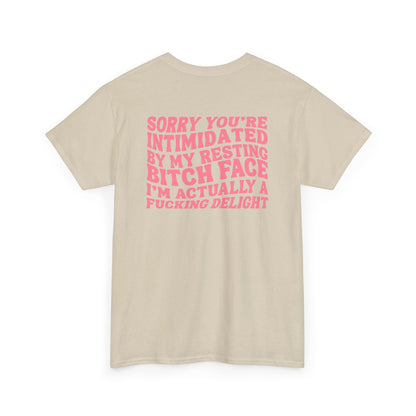 A sand t-shirt with a skeletal hand in a bubble on the front and the phrase “Sorry you’re intimidated by my resting Bitch ace I’m actually a fucking delight” on the back.