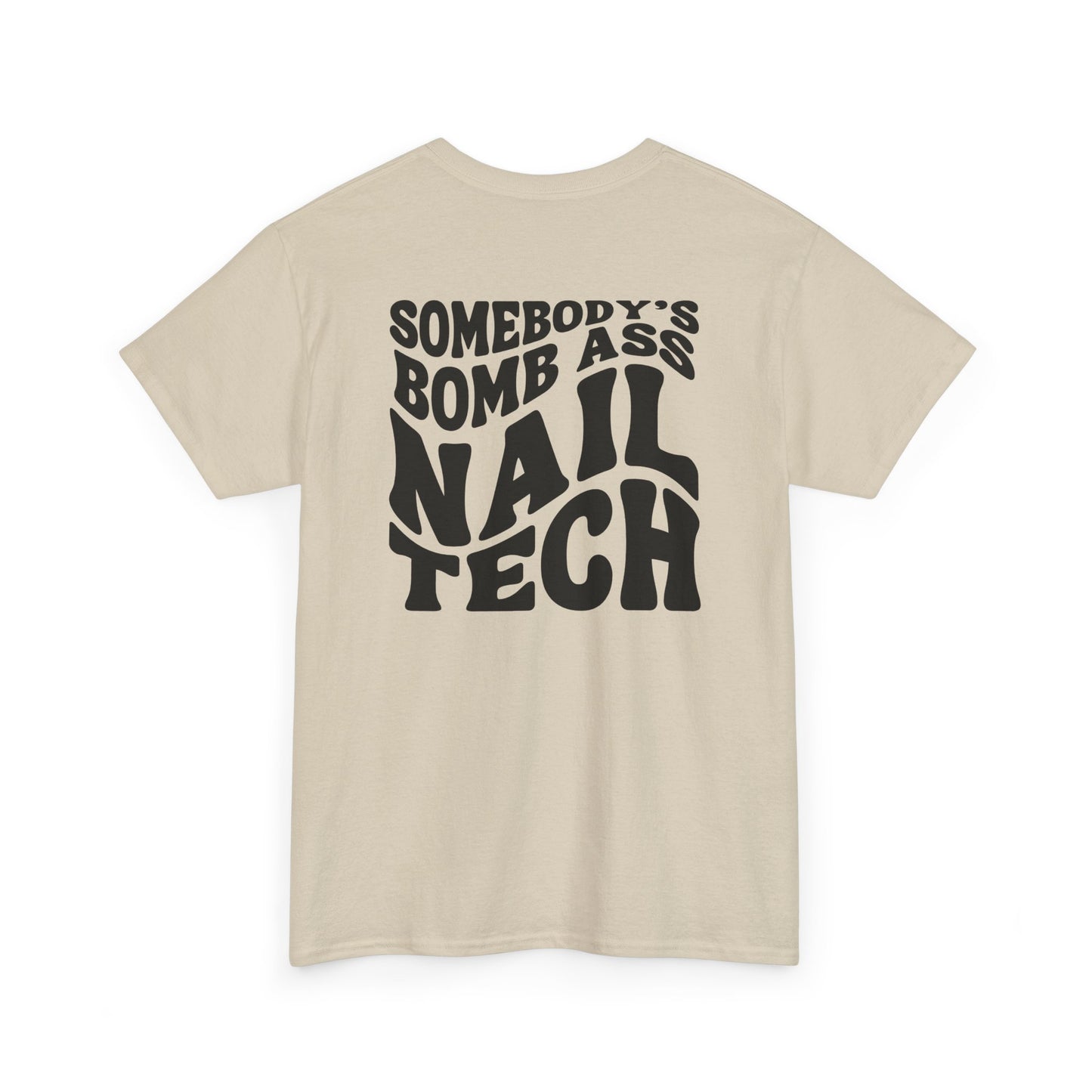 The words Somebody's Bomb Ass Nail Tech in a wavy font featured on a sand T-shirt. 