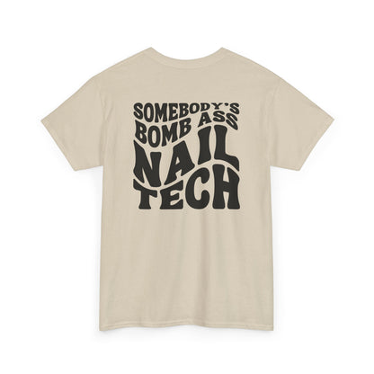 The words Somebody's Bomb Ass Nail Tech in a wavy font featured on a sand T-shirt. 