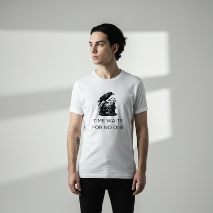 A male model wearing a A close-up of a t-shirt with a gothic illustration. A black crow stands atop a weathered skull, which has moss and delicate vines growing through its eye sockets and around its form, blending nature and death.